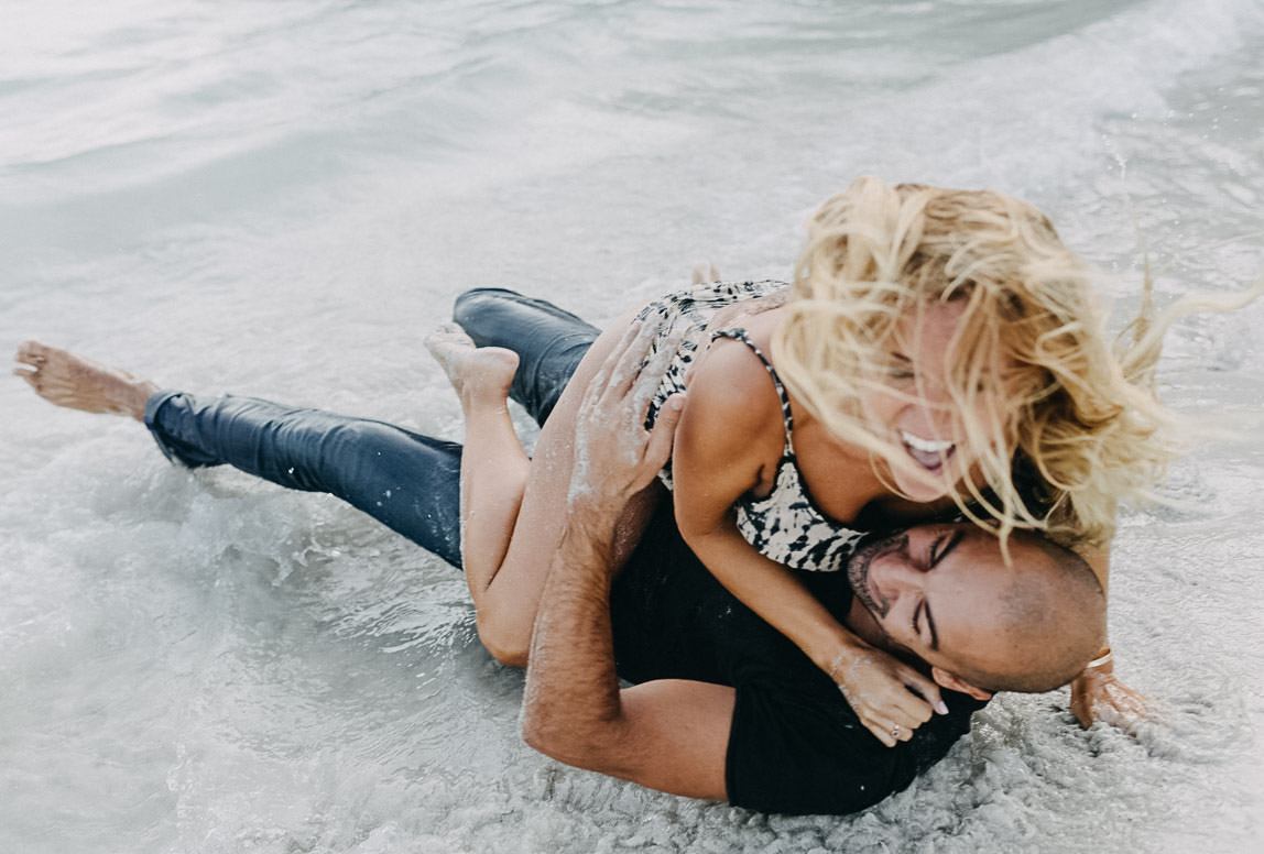 Paarfotos Mallorca: Liebespaar rollt verliebt im Sand beim Fotoshooting